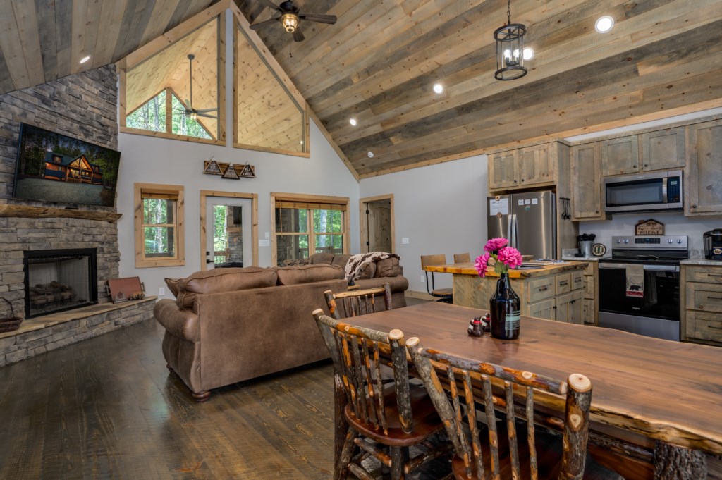 Rustic open-plan living area with cozy fireplace and modern kitchen amenities.