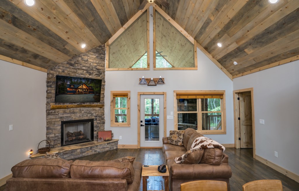 Rustic living room with vaulted ceilings, stone fireplace, and cozy seating for relaxation.