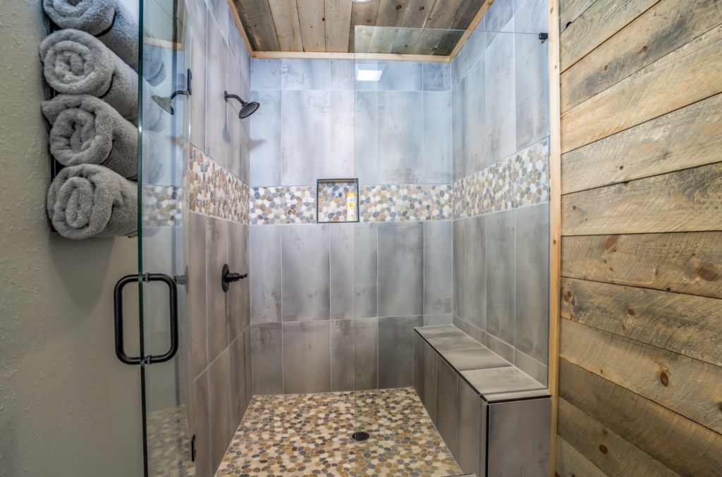 Rustic walk-in shower with stone tile accents and a convenient bench.