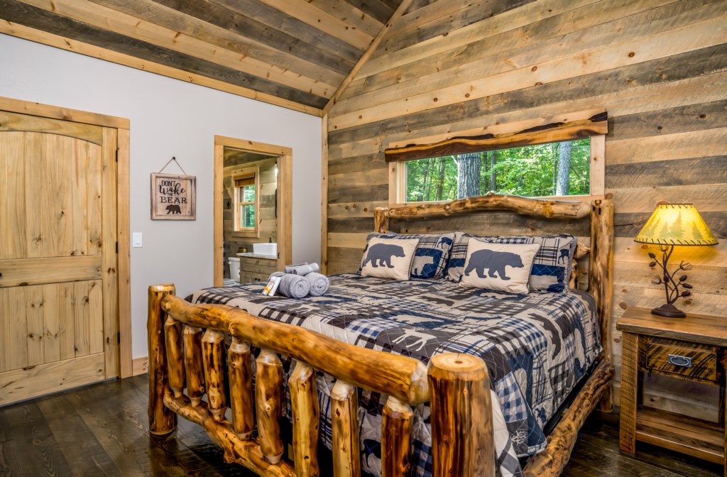 Rustic bedroom with log cabin decor and forest views, perfect for a cozy retreat.