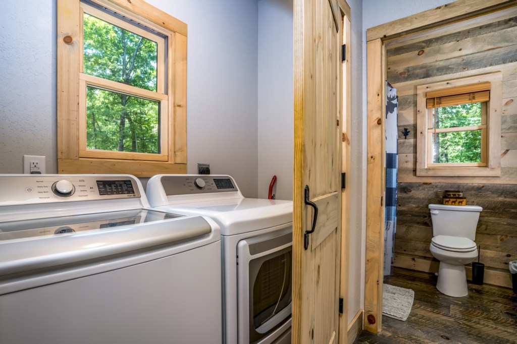 Convenient laundry room with forest views and adjacent rustic bathroom.