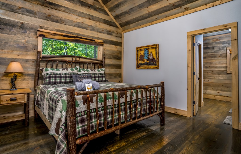 Rustic bedroom with woodland quilt and natural wood accents, offering a serene forest view.