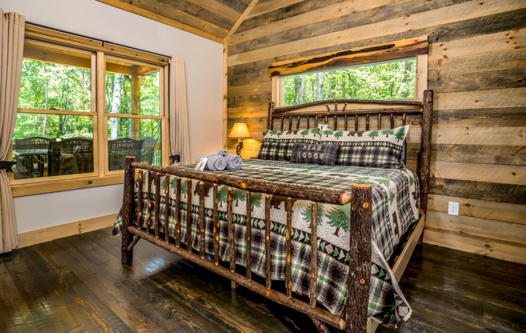 Rustic bedroom with wooded views and cozy log bed, perfect for a peaceful retreat.
