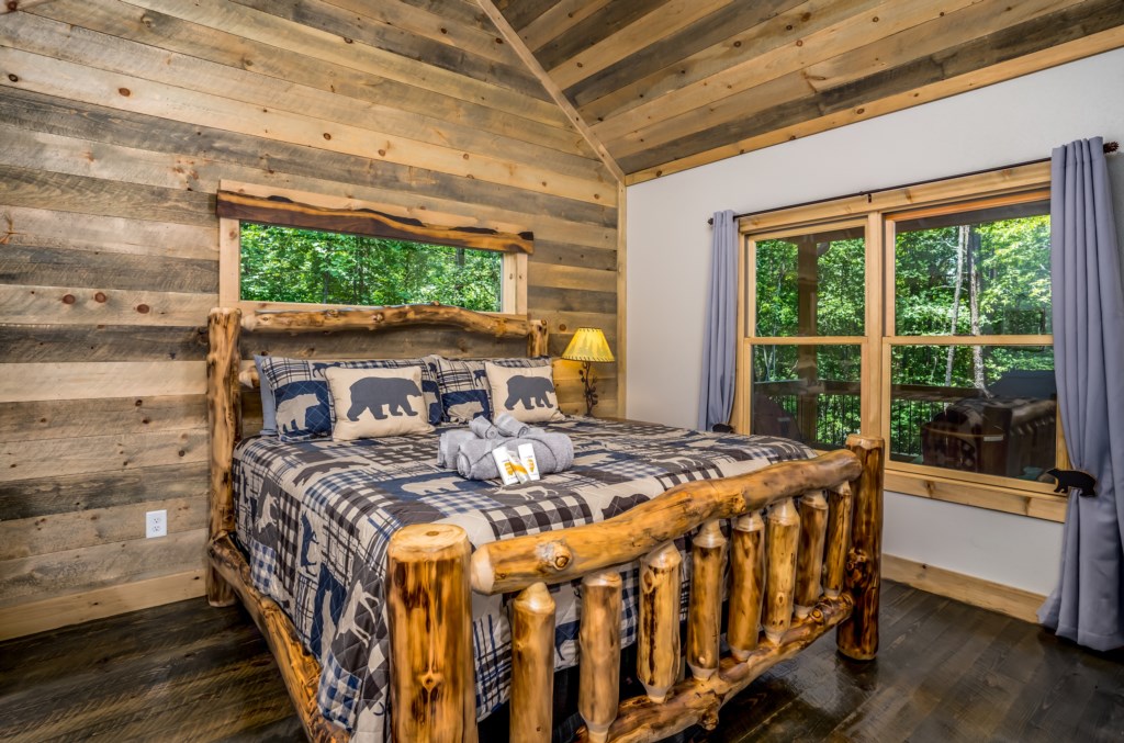 Rustic bedroom with log bed and forest views, perfect for a cozy mountain retreat.