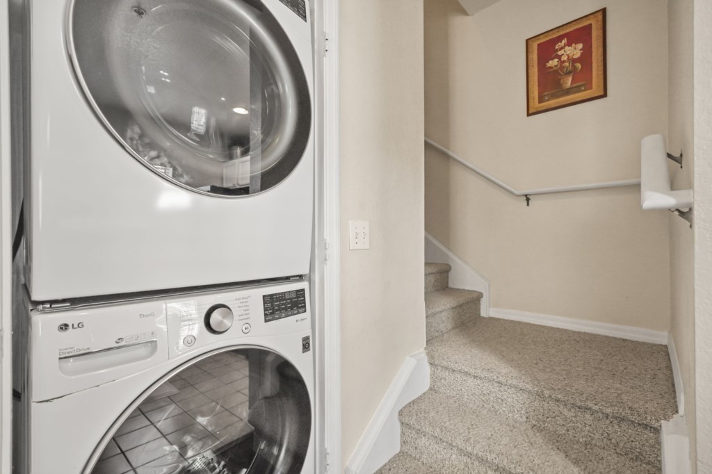 Laundry area with washer & dryer downstairs & the stairs leading upstairs in the background.