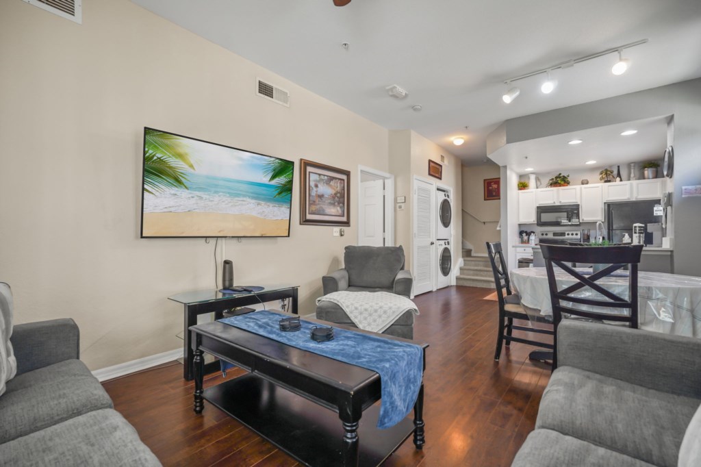 Living room with Smart TV, dining area, laundry area, & the kitchen in the background.