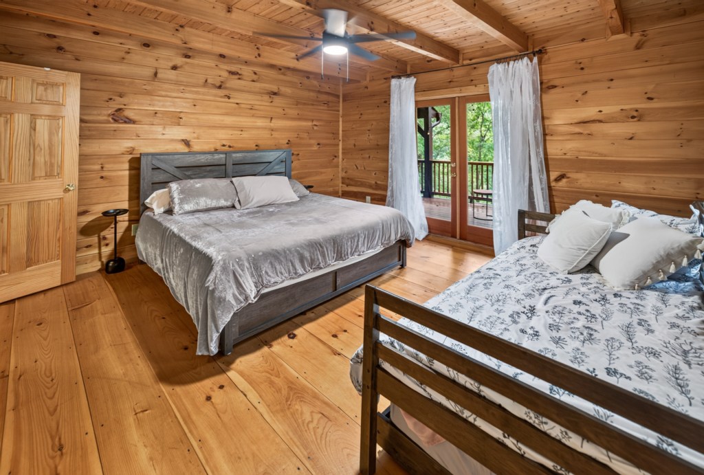 Charming rustic bedroom with wooden walls and a private balcony view.