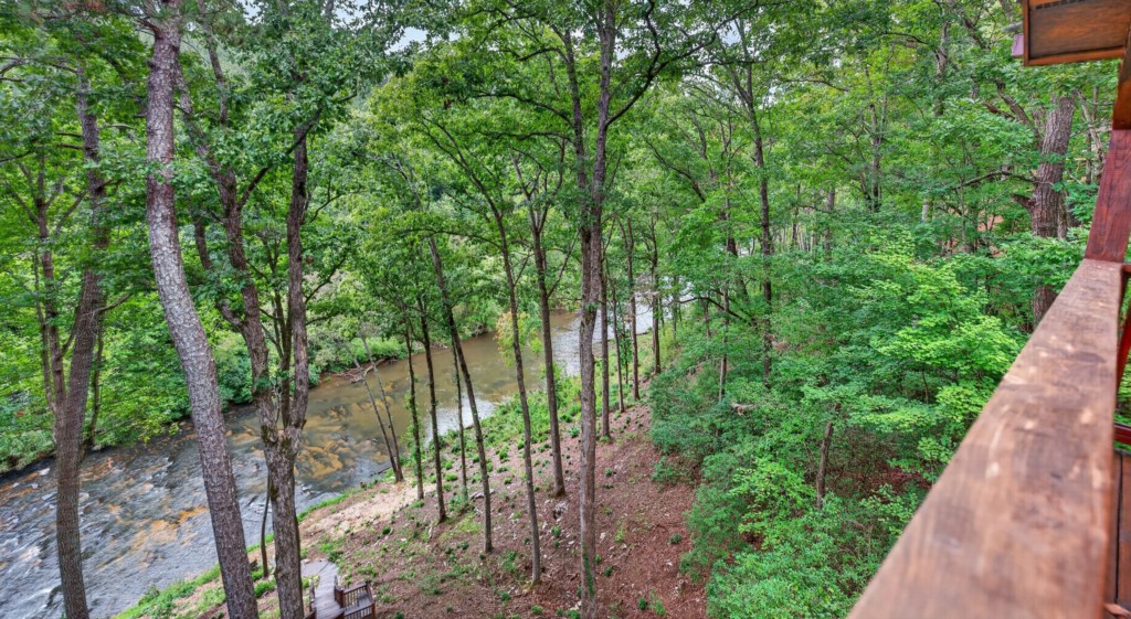 Serene balcony view overlooking a lush forest and tranquil river.