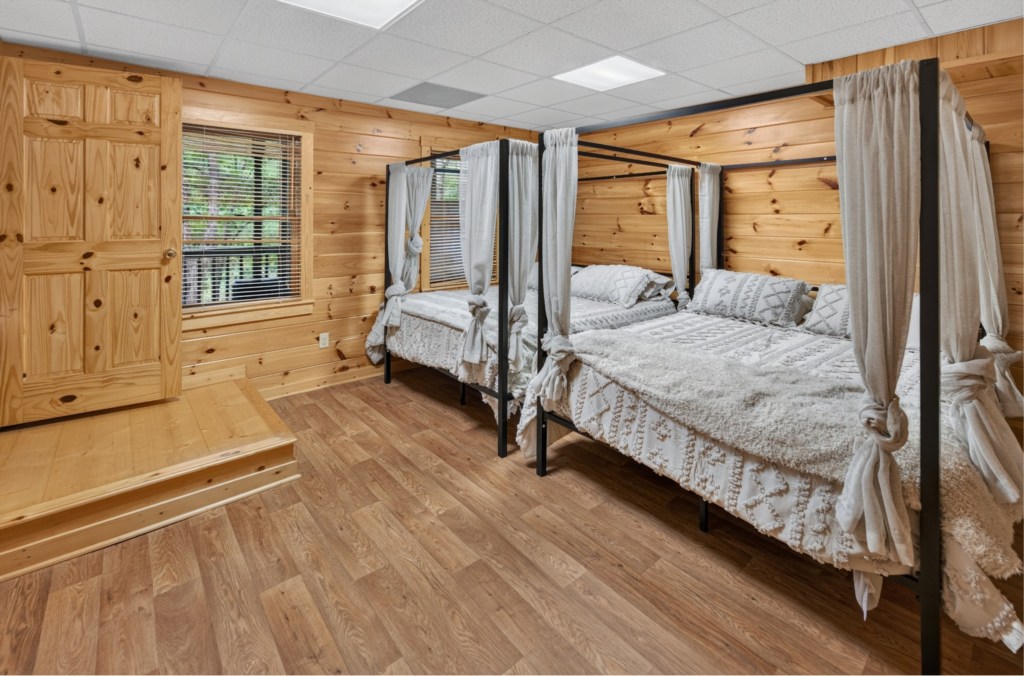 Charming wood-paneled bedroom with cozy canopy beds and natural light.