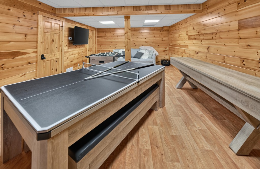 Rustic game room with ping pong, foosball, and shuffleboard for family fun.