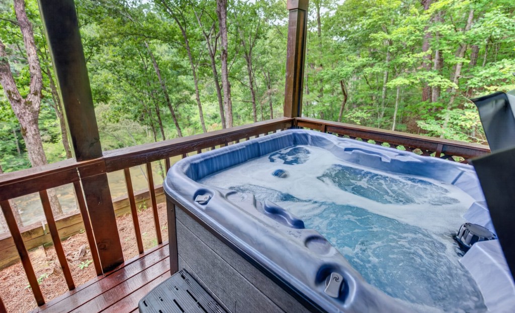 Relax in the private hot tub with serene forest views.