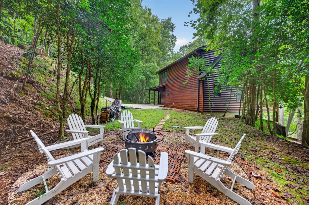 Serene outdoor firepit area with Adirondack chairs, perfect for evening gatherings in nature.