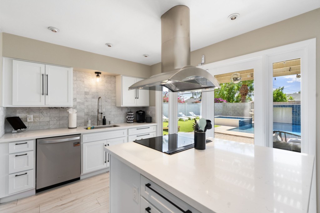 Modern kitchen with pool view and sleek stainless steel appliances.