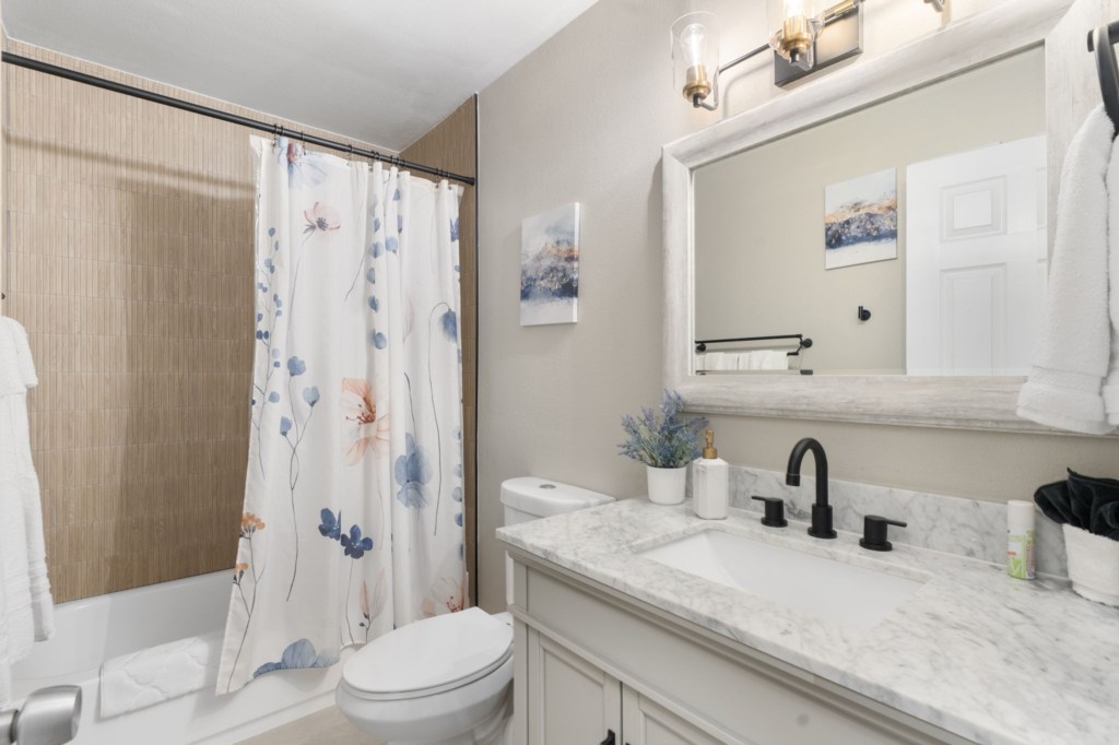 Elegant bathroom with marble countertop and floral shower curtain.