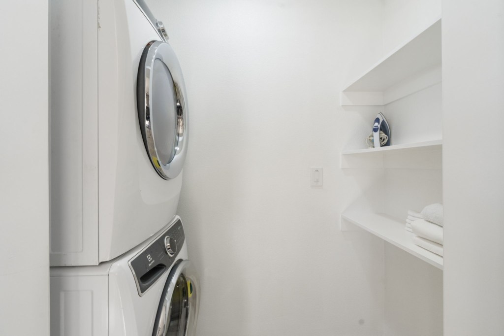 Convenient laundry area with stacked washer and dryer plus ironing essentials.