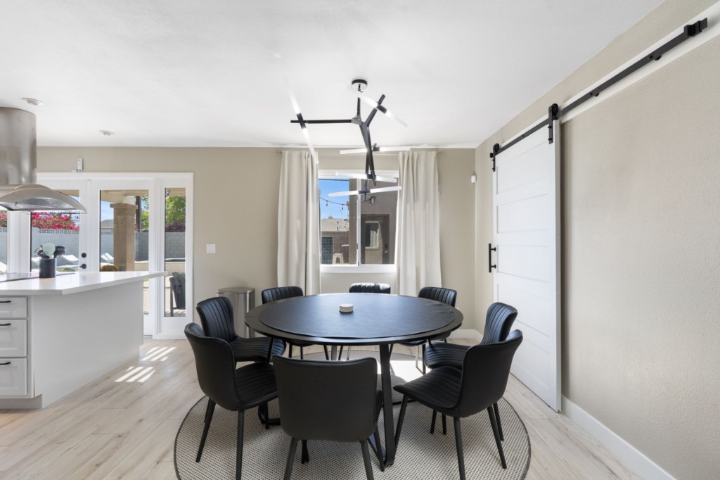 Modern dining area with seating for six, adjacent to a bright kitchen and patio access.